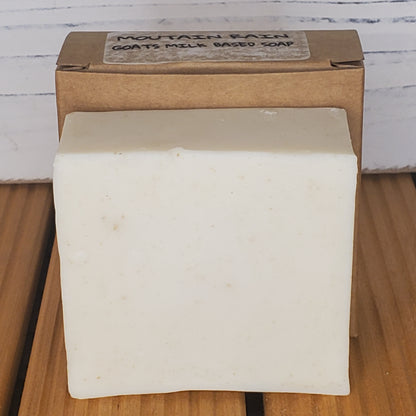 Bar of soap on a wooden surface with a cardboard box labeled 'MOUNTAIN GROVE SOAP' in the background.