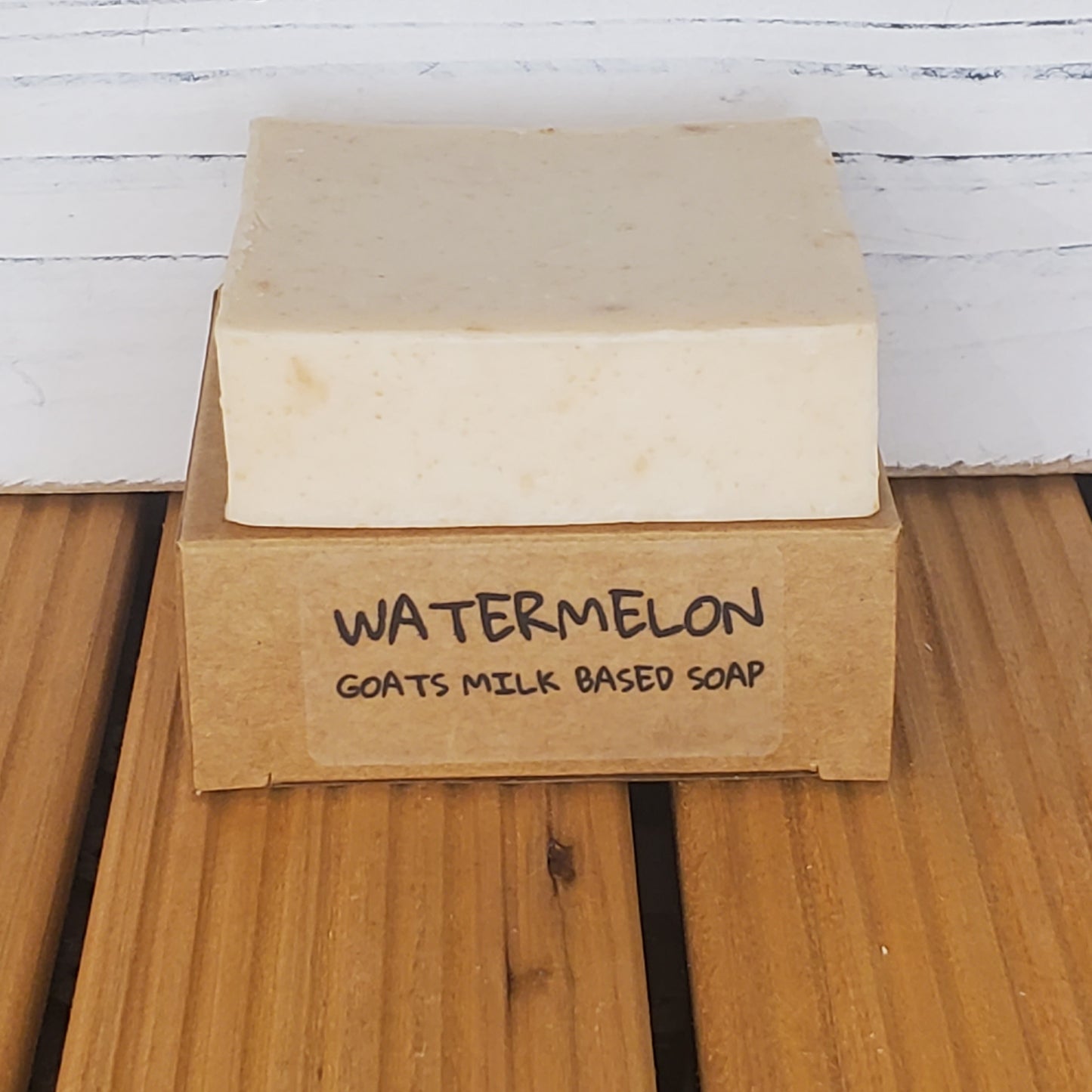 Bar of watermelon goat's milk soap on a wooden block with a wooden background