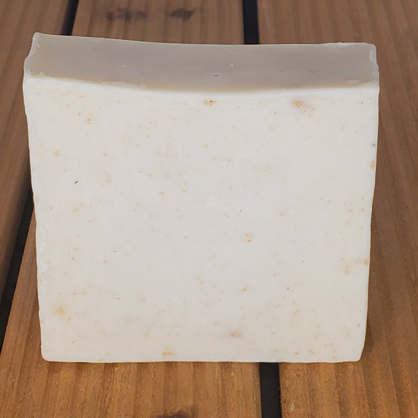 Rectangular block of white soap on a wooden surface