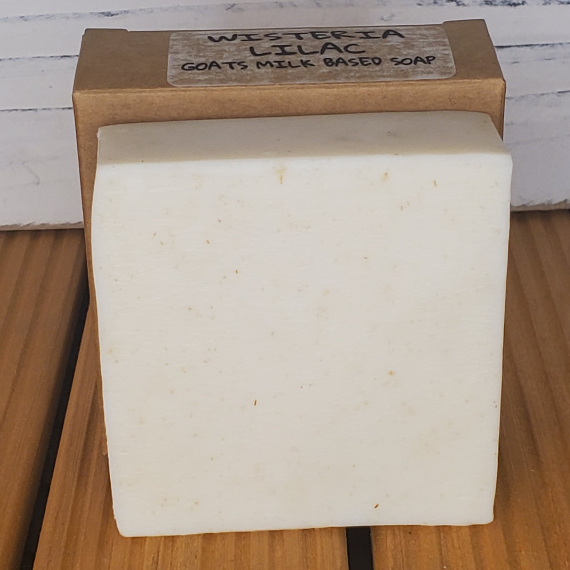 Bar of soap with a wooden box labeled 'Wisteria Lilac' on a wooden surface.