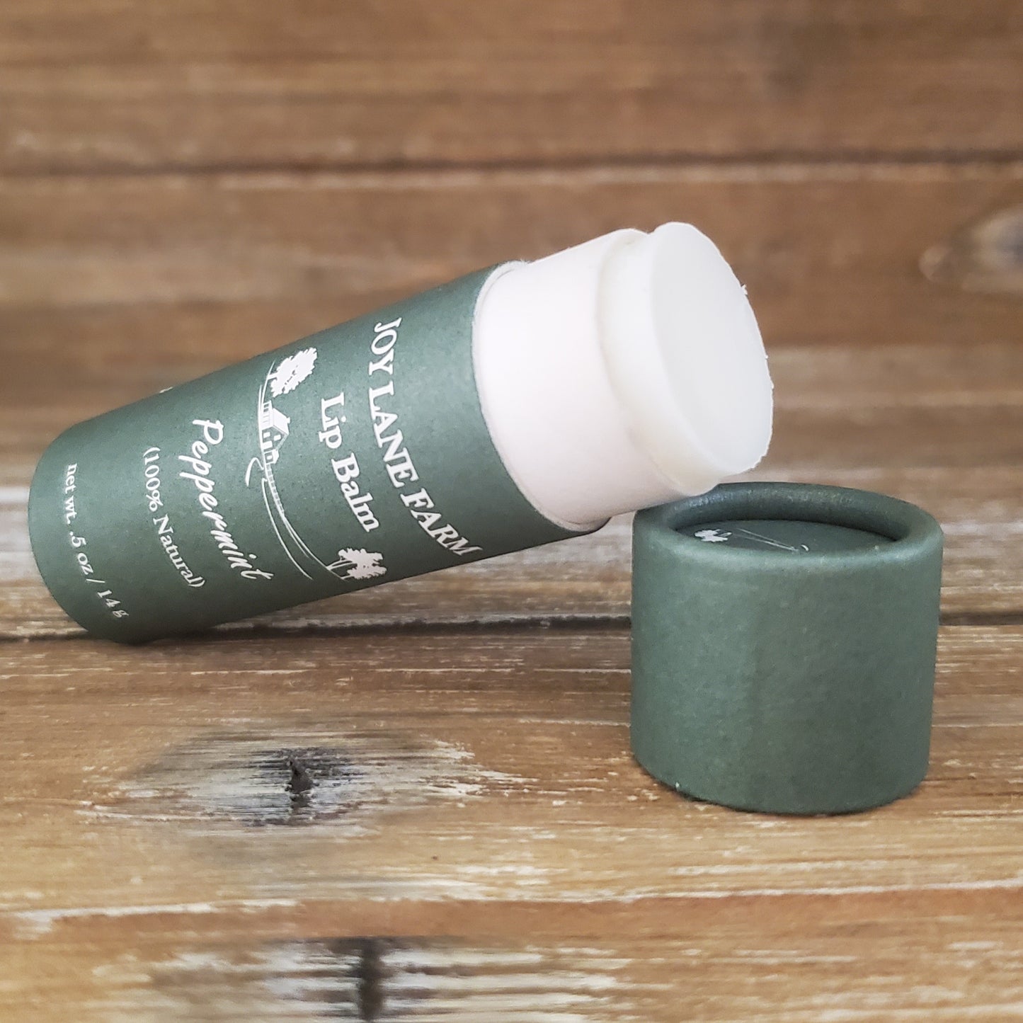 Lip balm with green container and white cap on a wooden surface