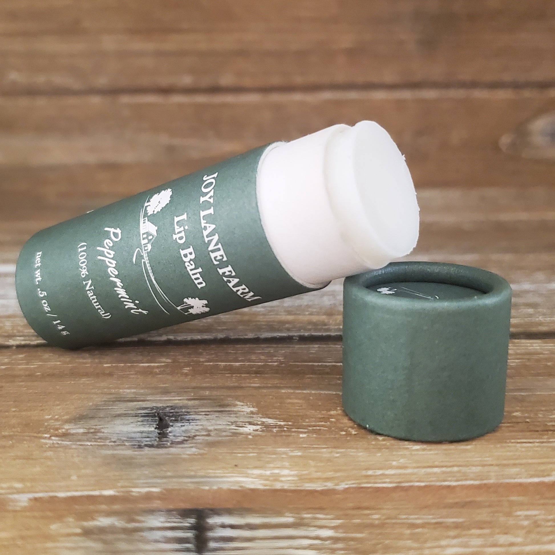 Lip balm with green container and white cap on a wooden surface