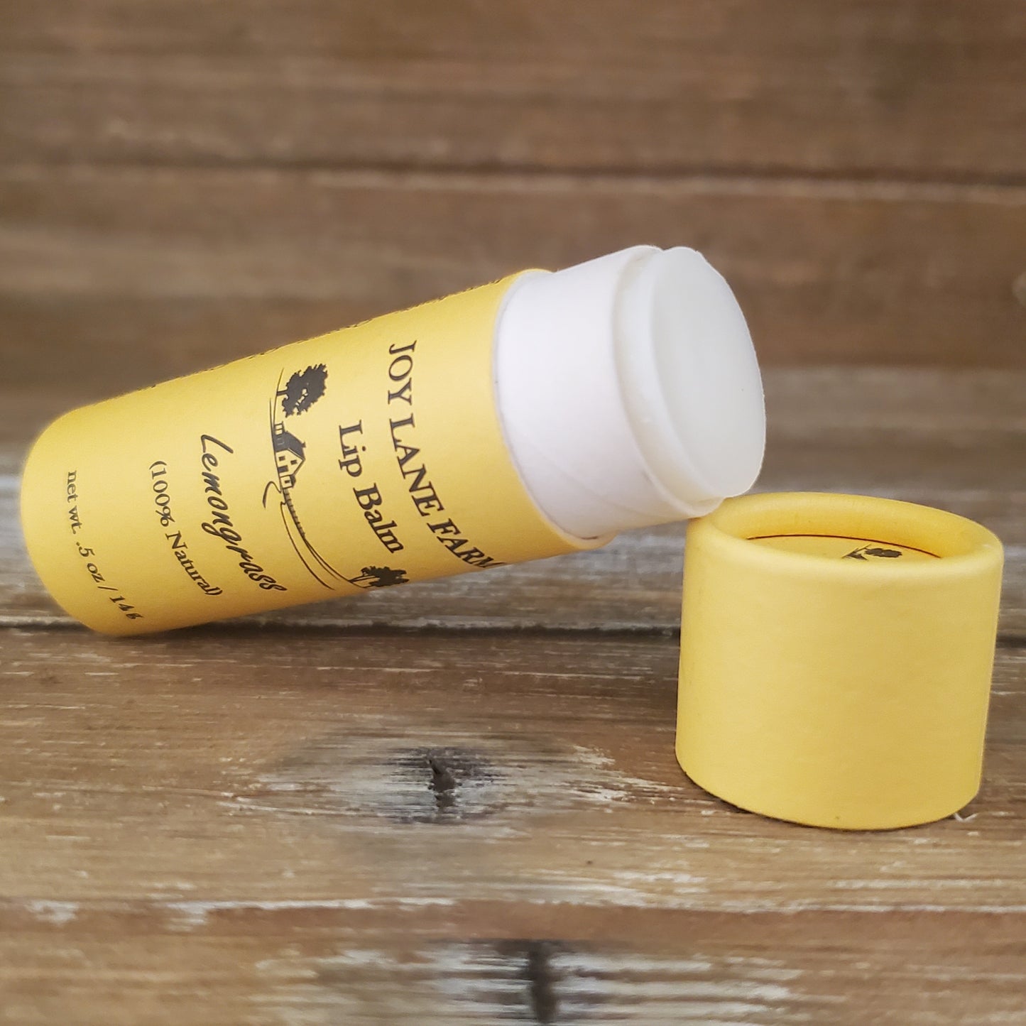 Yellow lip balm with white cap on a wooden surface
