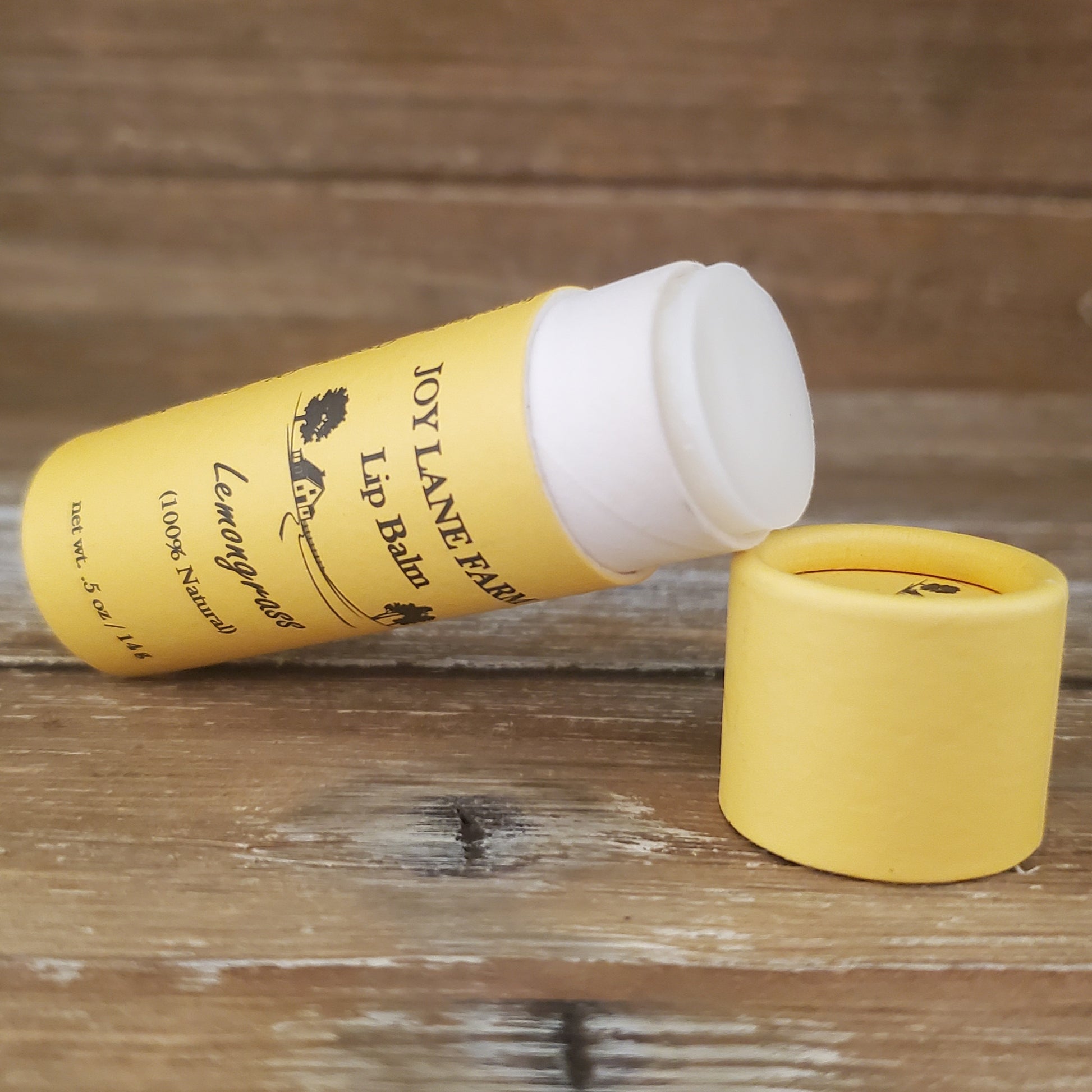 Yellow lip balm with white cap on a wooden surface