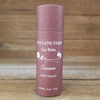 Lip balm container with 'Joy Lane Farm' branding on a wooden background