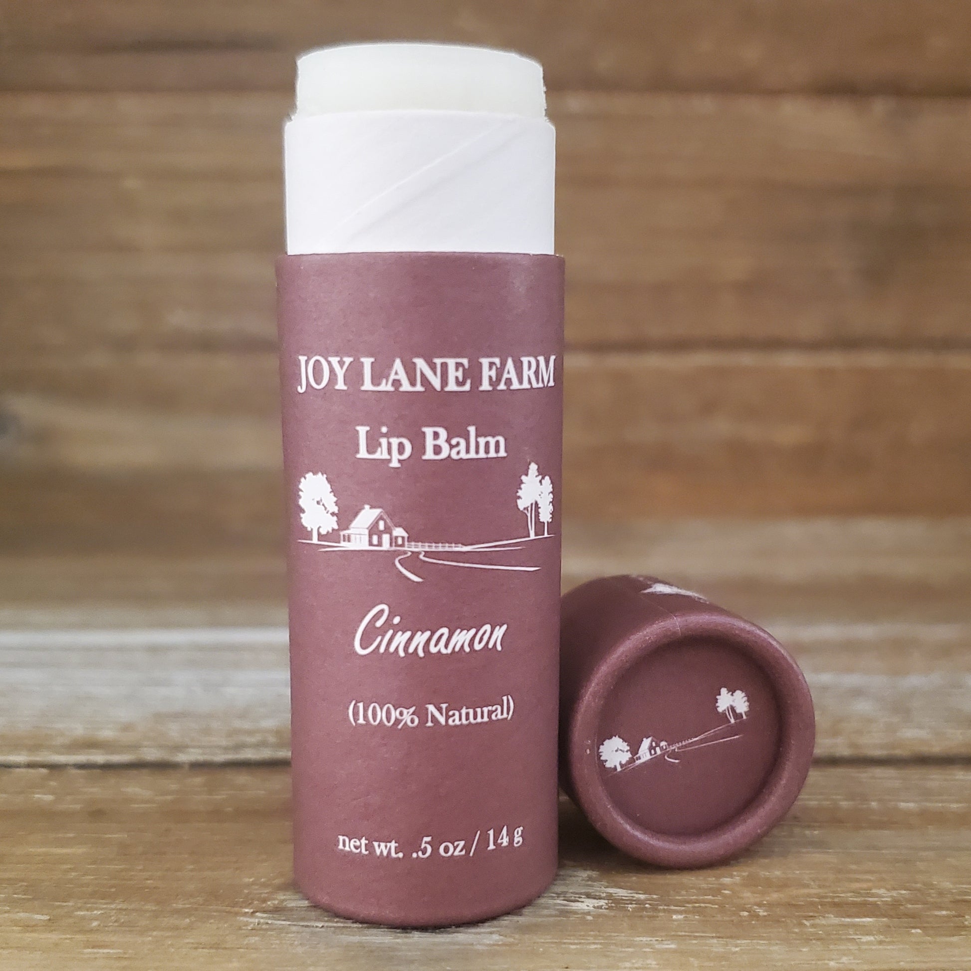 Lip balm container with 'Joy Lane Farm' branding on a wooden background