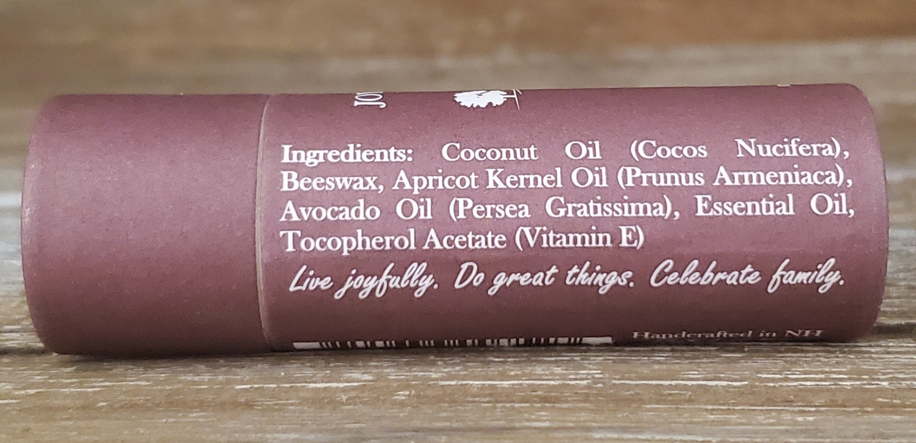 Roll of lip balm with ingredients listed on a wooden surface