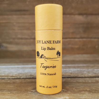 Lip balm container with 'Joy Lane Farm' branding on a wooden background