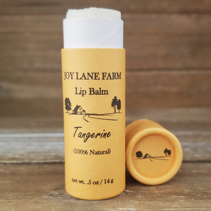 Lip balm tube from Joy Lane Farm on a wooden surface with a blurred background