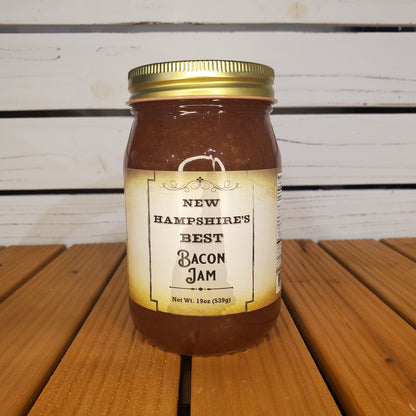 Jar of New Hampshire's Best Bacon Jam on a wooden surface with a white slatted background