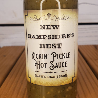 Bottle of 'New Hampshire's Best Kickin' Pickle Hot Sauce' on a wooden surface.
