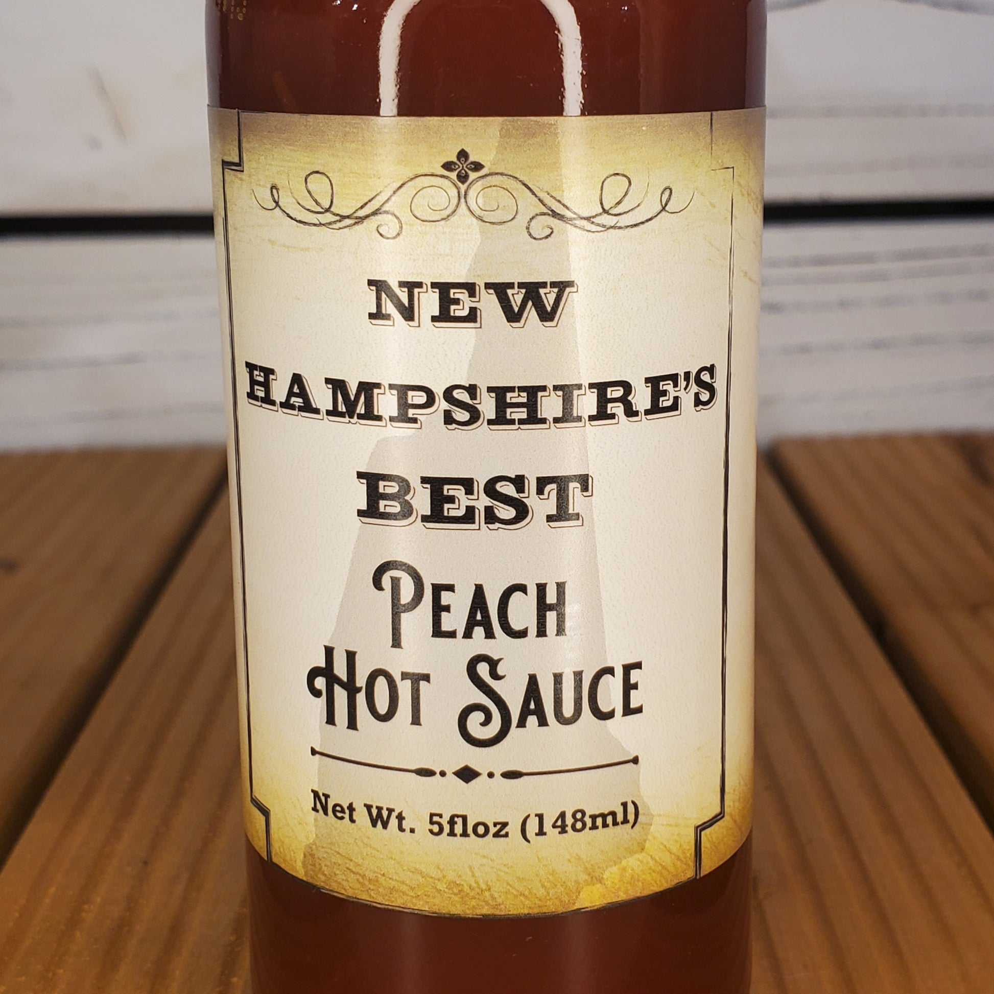 Bottle of New Hampshire's Best Peach Hot Sauce on a wooden surface