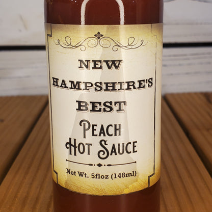 Bottle of New Hampshire's Best Peach Hot Sauce on a wooden surface