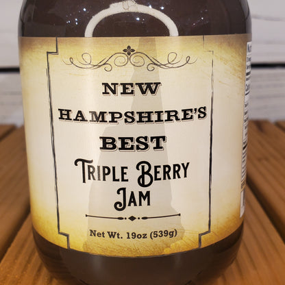 Bottle of New Hampshire's Best Triple Berry Jam with a label on a wooden surface.