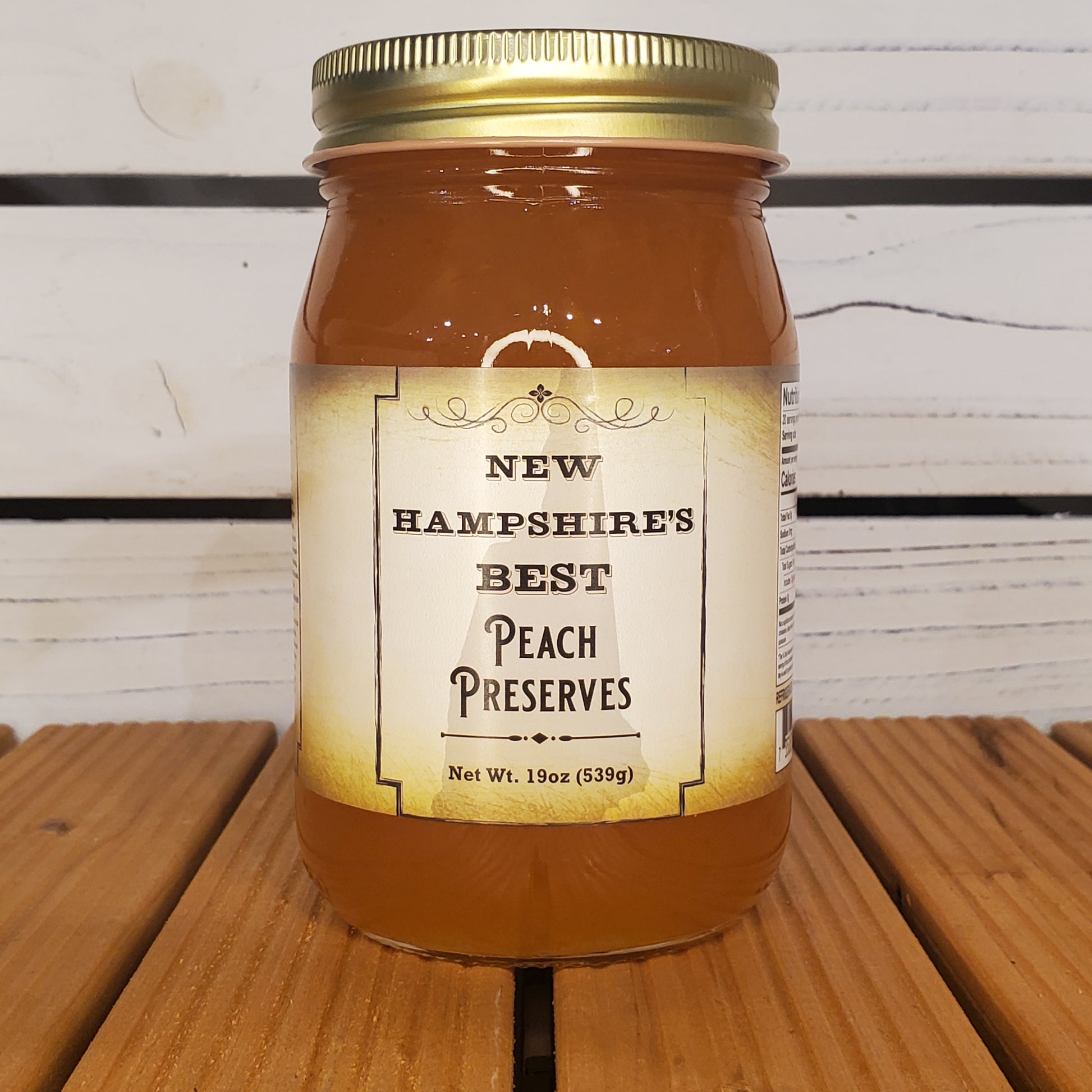 Jar of New Hampshire's Best Peach Preserves on a wooden surface