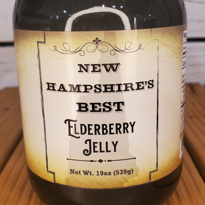 Bottle of New Hampshire's Best Elderberry Jelly with a label on a wooden surface.