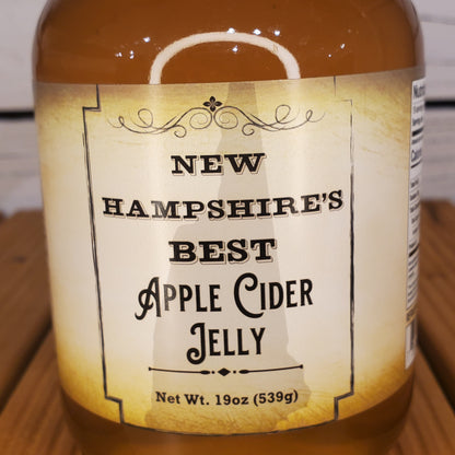 Bottle of New Hampshire's Best Apple Cider Jelly with a label on a wooden surface.