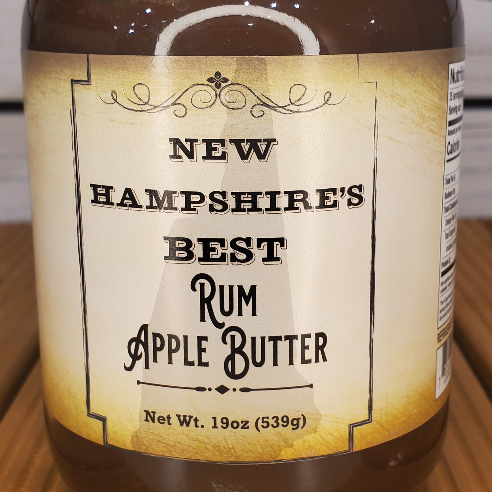 Jar of New Hampshire's Best Rum Apple Butter with label on a wooden surface