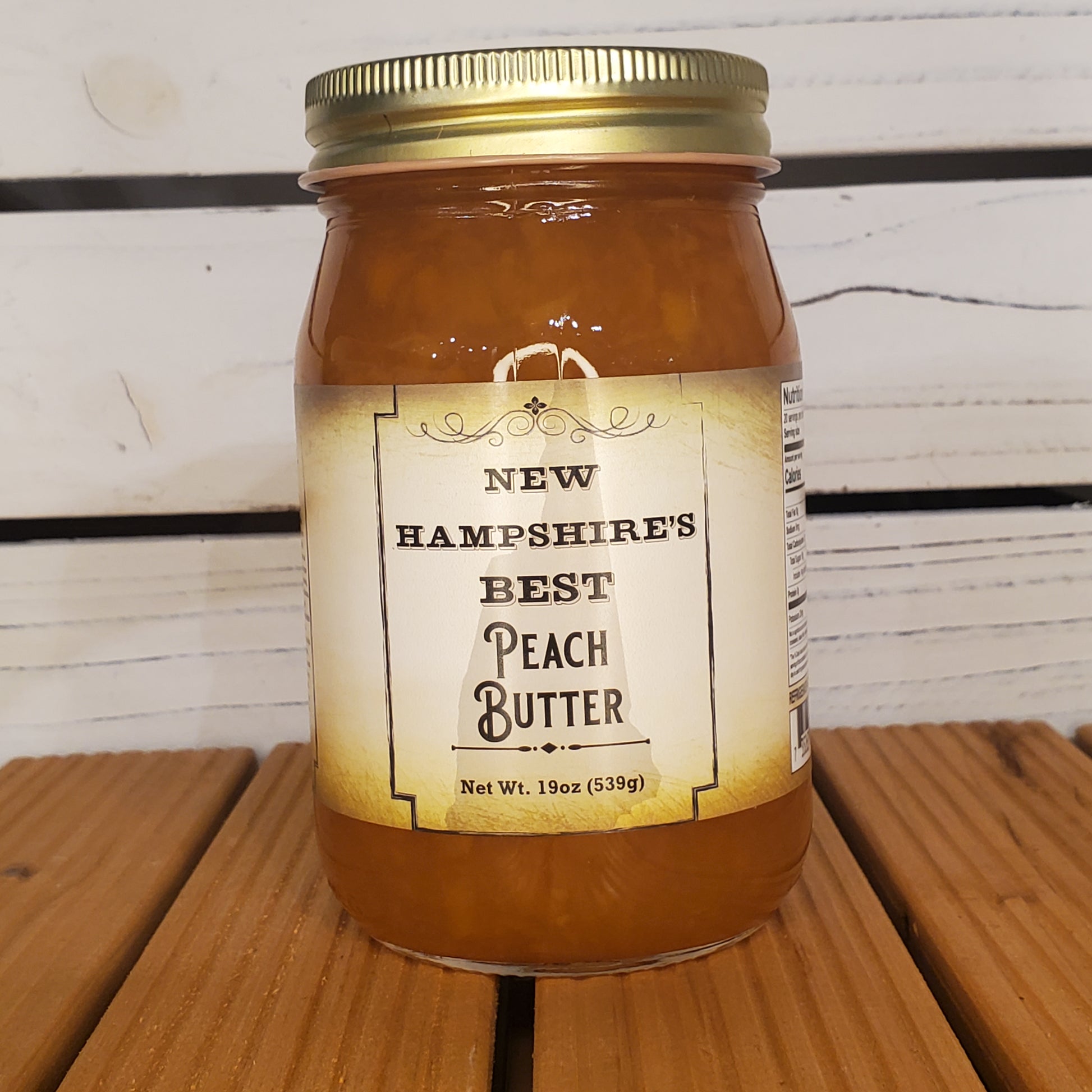 Jar of New Hampshire's Best Peach Butter on a wooden surface