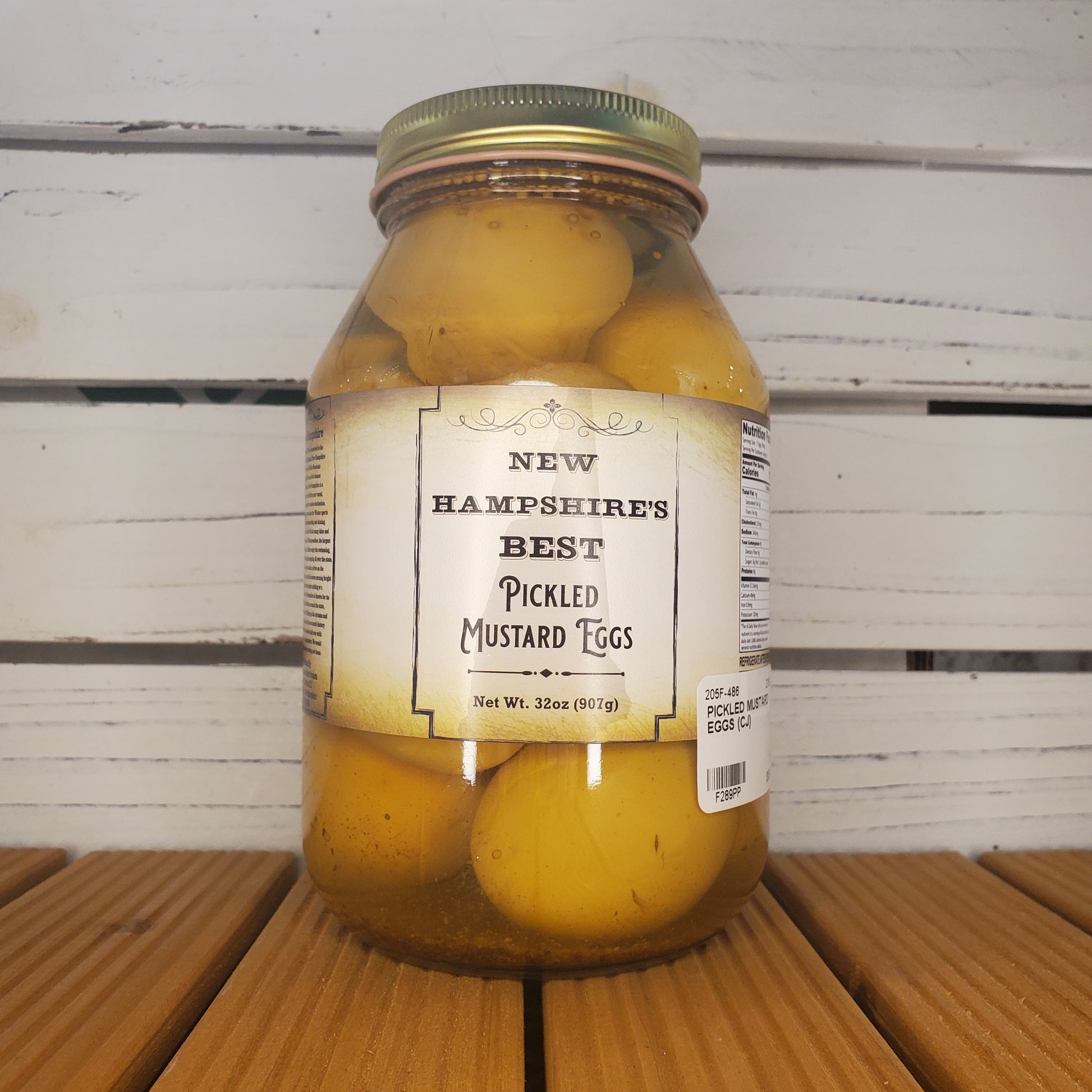 Jar of pickled mustard cobs with a label on a wooden surface