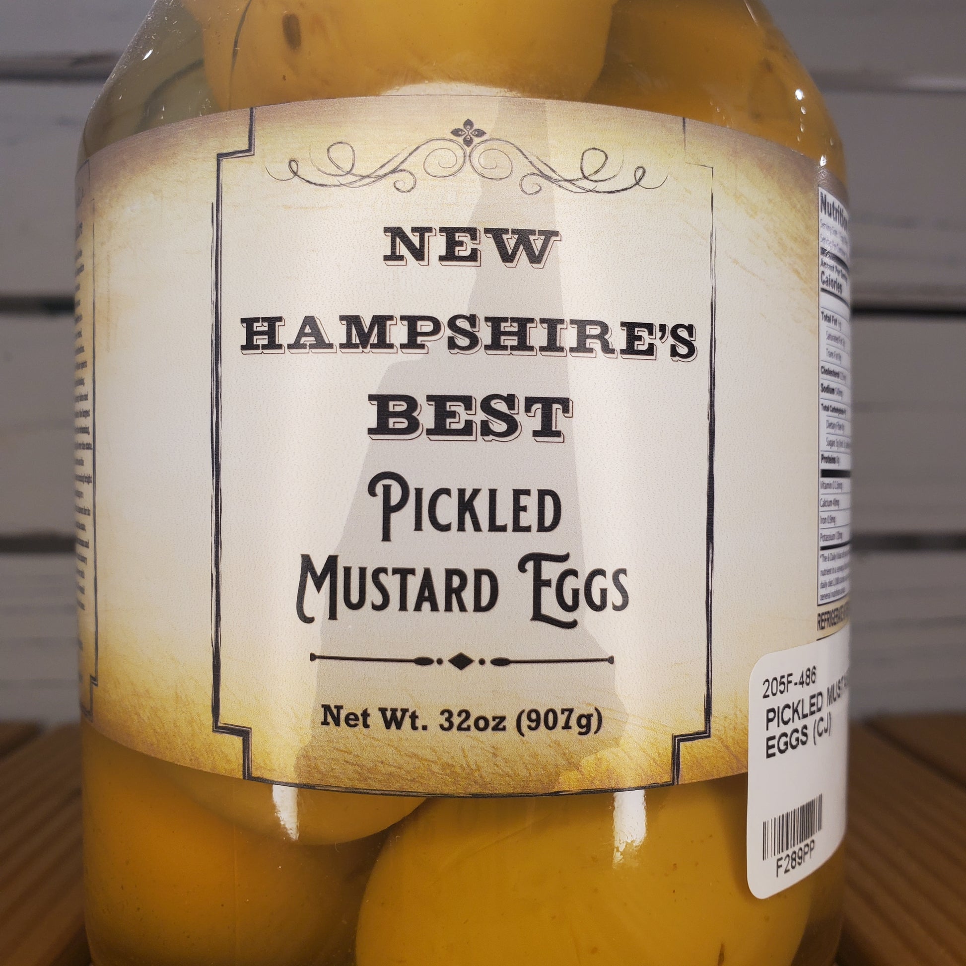 Jar of pickled mustard eggs with a label on a white background