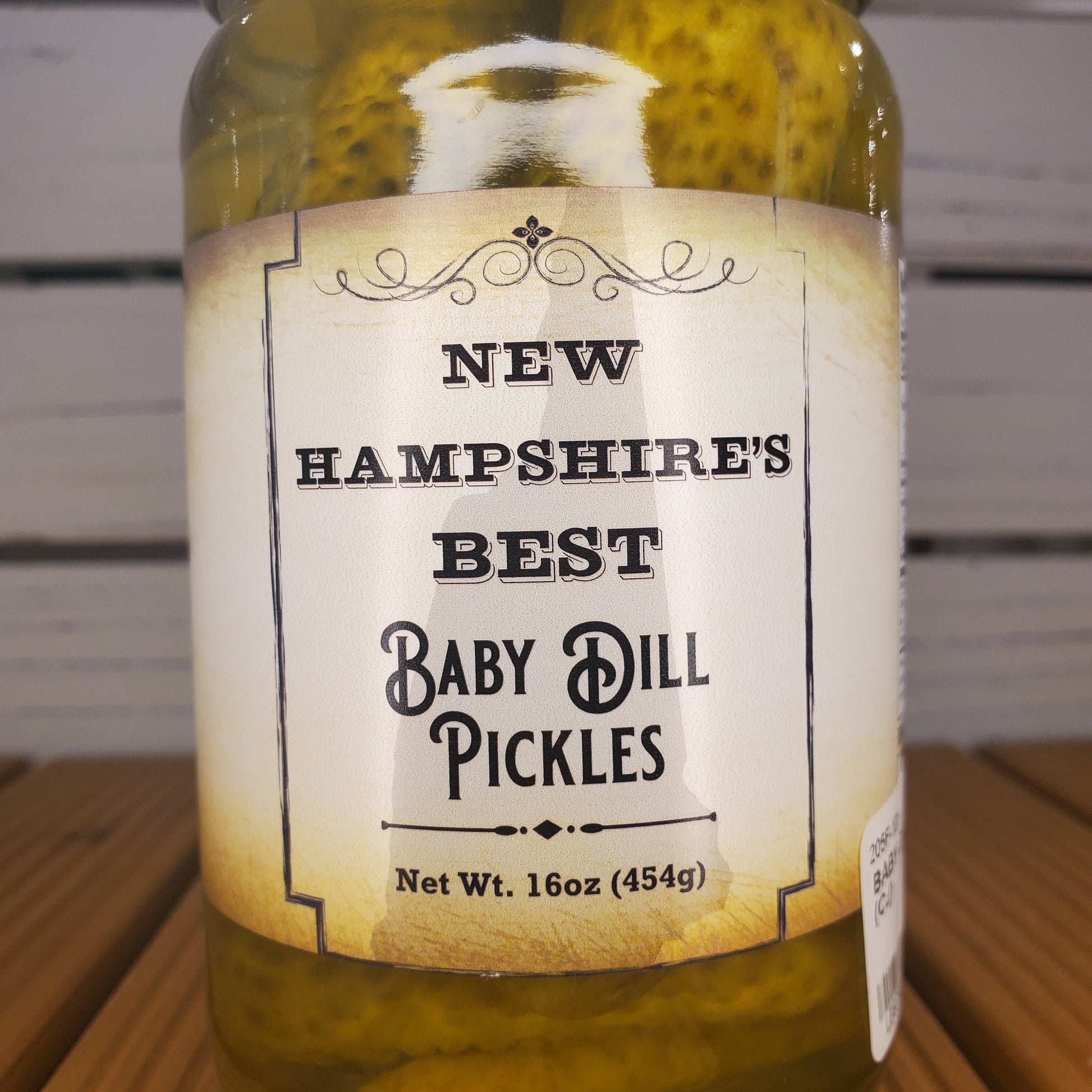 Bottle of New Hampshire's Best Baby Dill Pickles with a label on a wooden surface.
