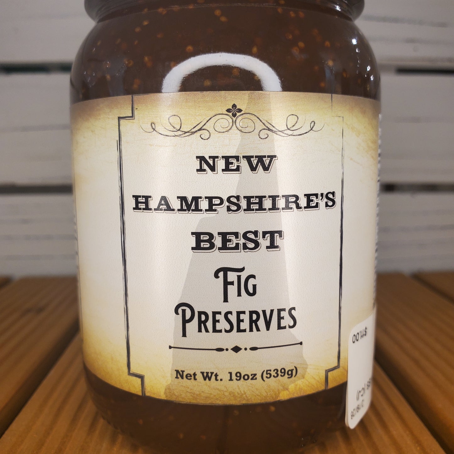 Jar of New Hampshire's Best Fig Preserves with a label on a wooden surface.