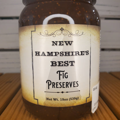 Jar of New Hampshire's Best Fig Preserves with a label on a wooden surface.