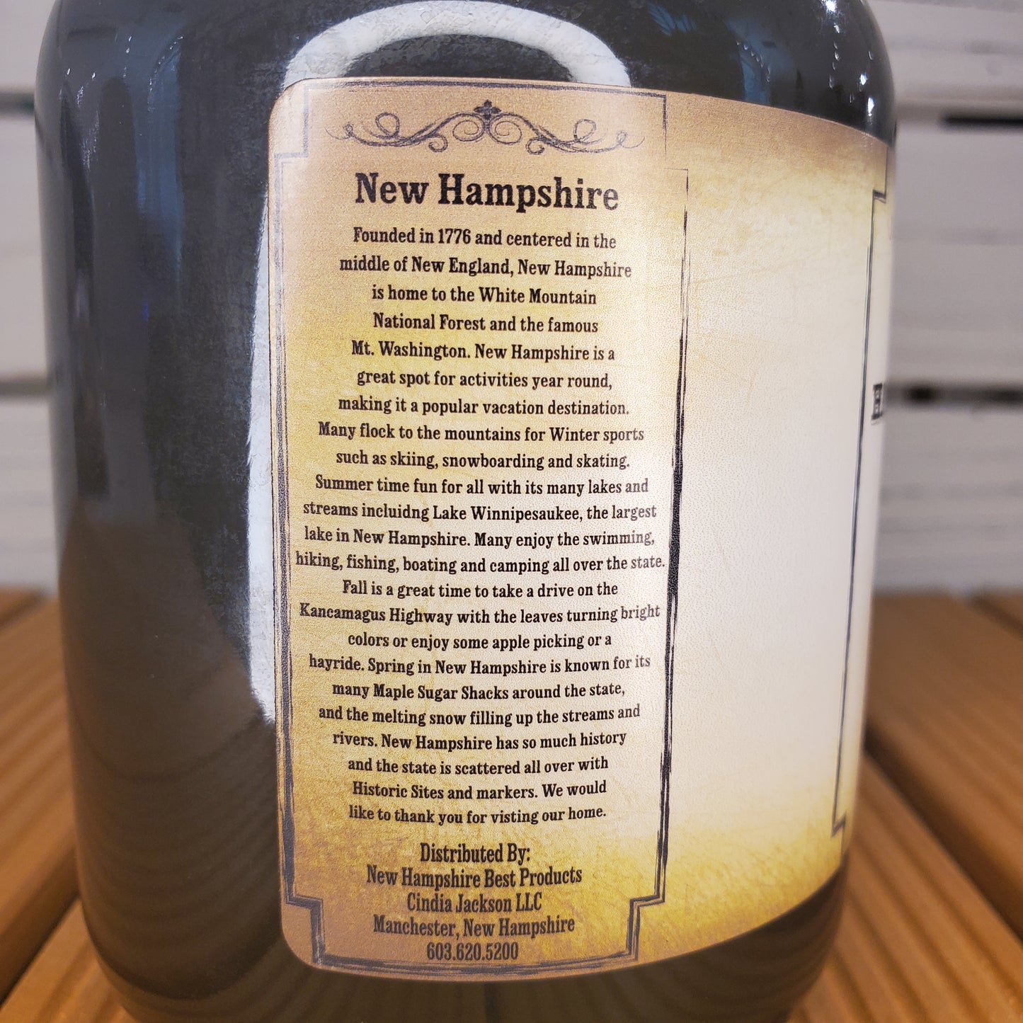 Bottle with a label detailing New Hampshire history on a wooden surface.