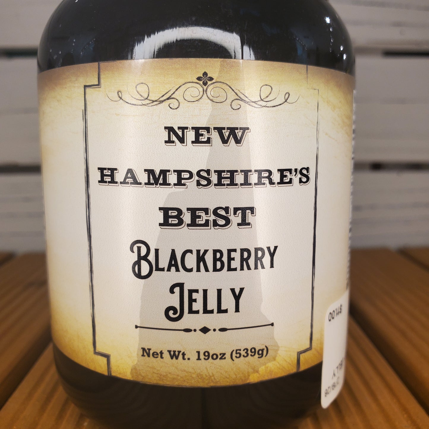 Bottle of New Hampshire's Best Blackberry Jelly with a label on a wooden surface.