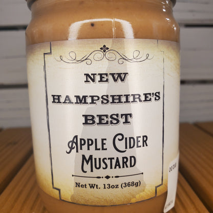 Bottle of New Hampshire's Best Apple Cider Mustard with a label on a wooden surface.