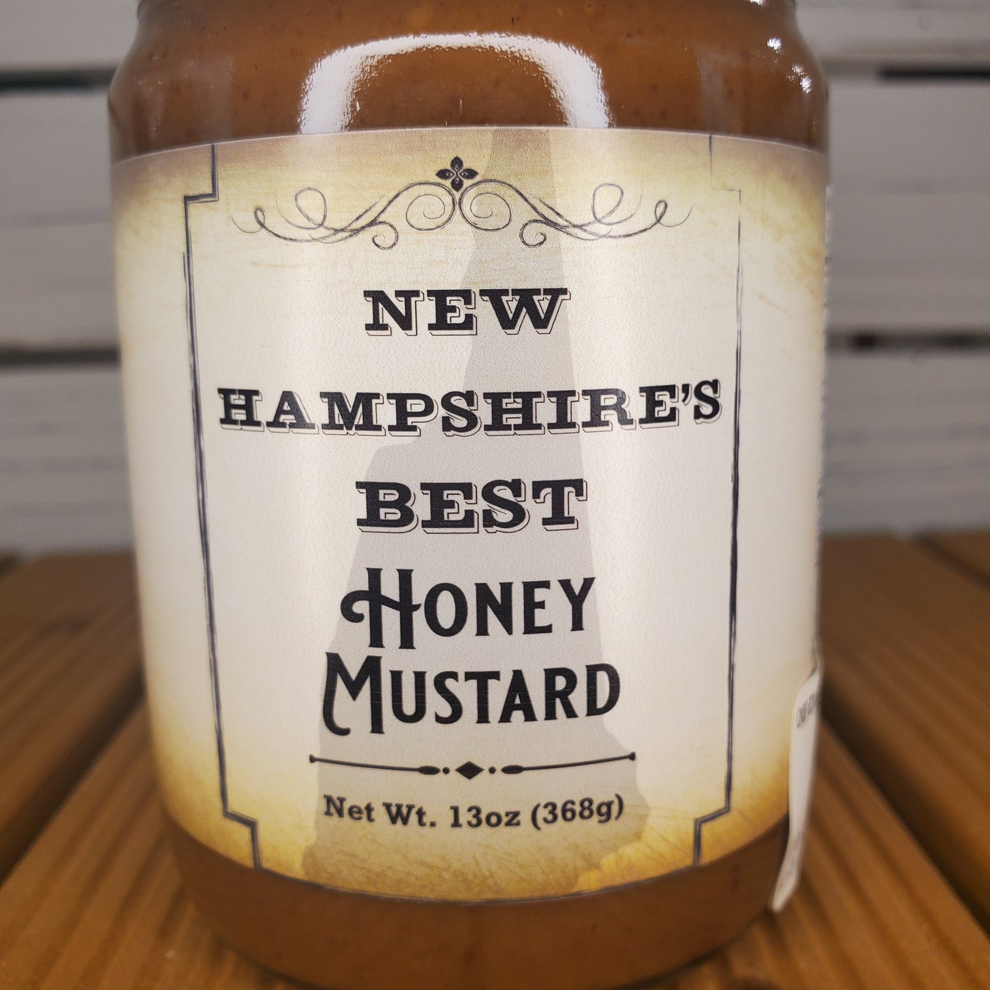 Jar of New Hampshire's Best Honey Mustard with a label on a wooden surface.