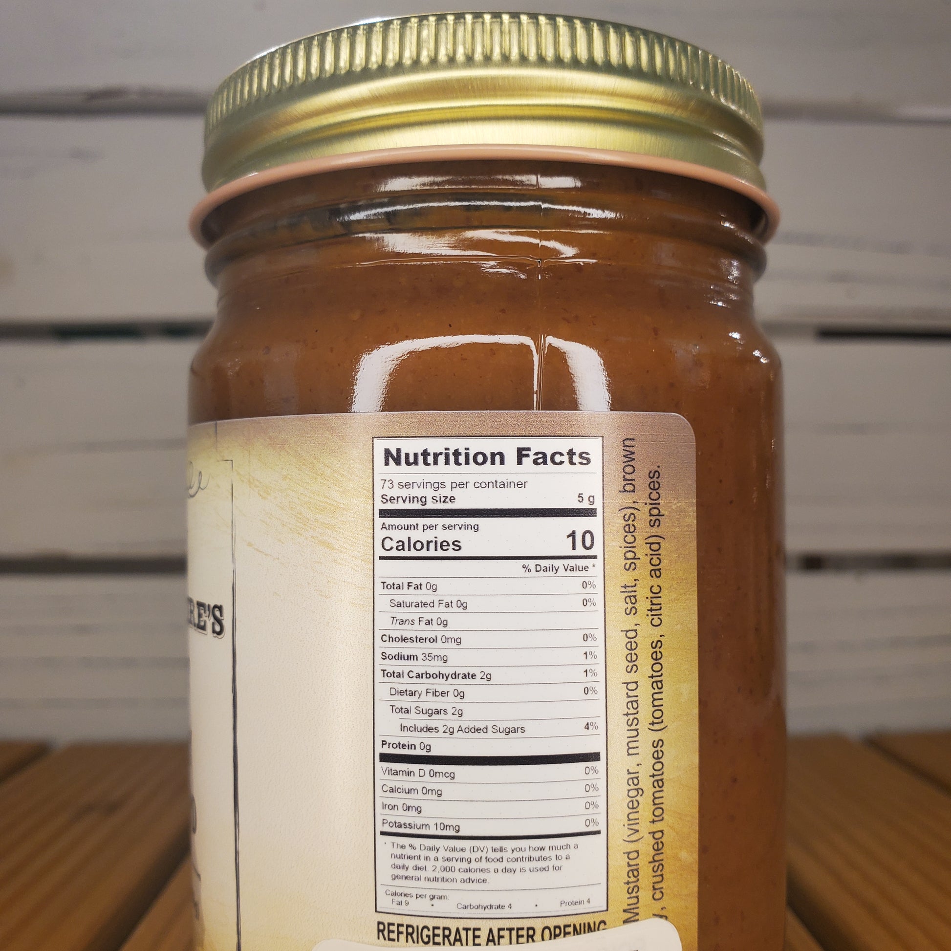 Jar with a gold lid and nutrition label on a wooden surface