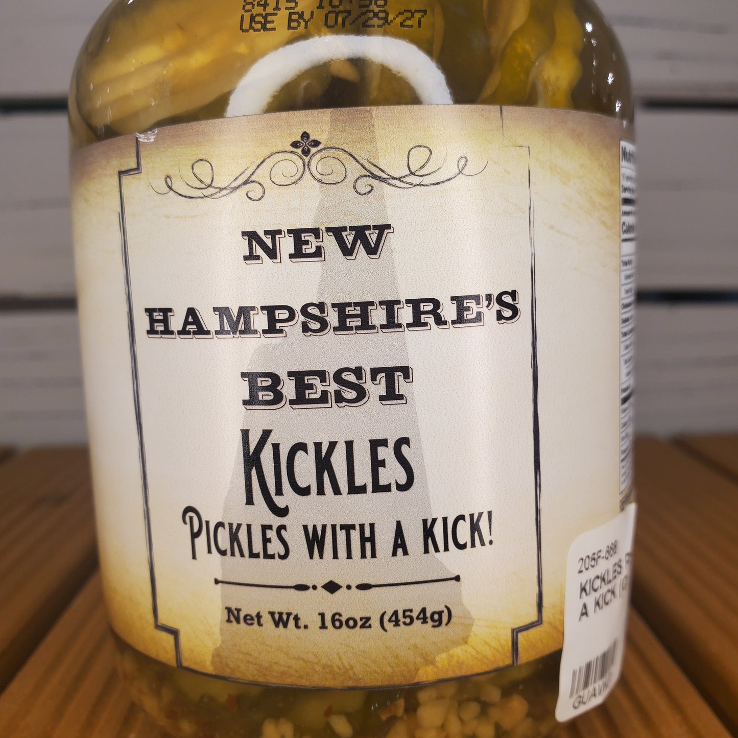 Bottle of New Hampshire's Best Kickles Pickles with a Kick label on a wooden surface.