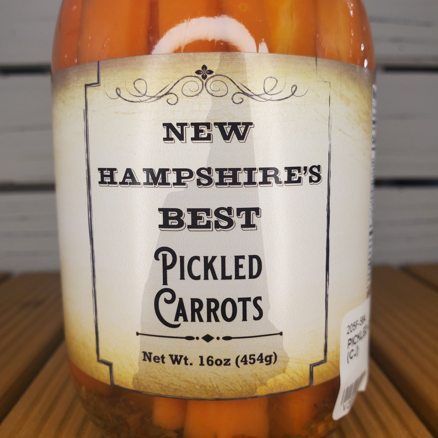 Jar of New Hampshire's Best Pickled Carrots with a label on a wooden surface.