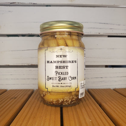 Jar of pickled baby corn with a label on a wooden surface