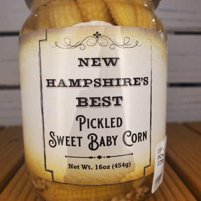 Jar of pickled sweet baby corn with a label on a wooden surface