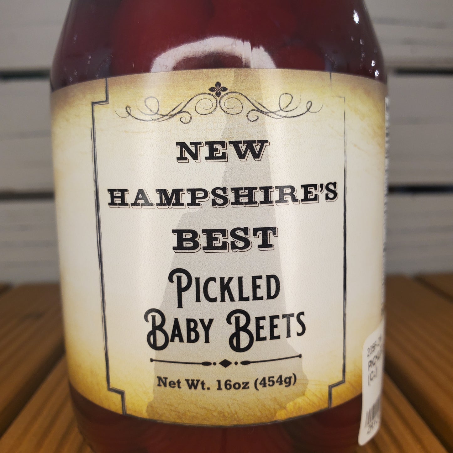 Jar of pickled baby beets with a label on a wooden surface