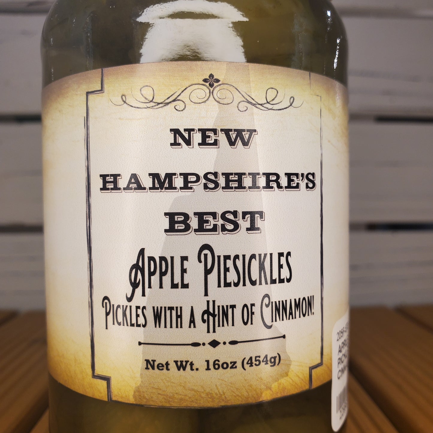 Bottle of New Hampshire's Best Apple Pie Pickles with a label on a wooden surface.