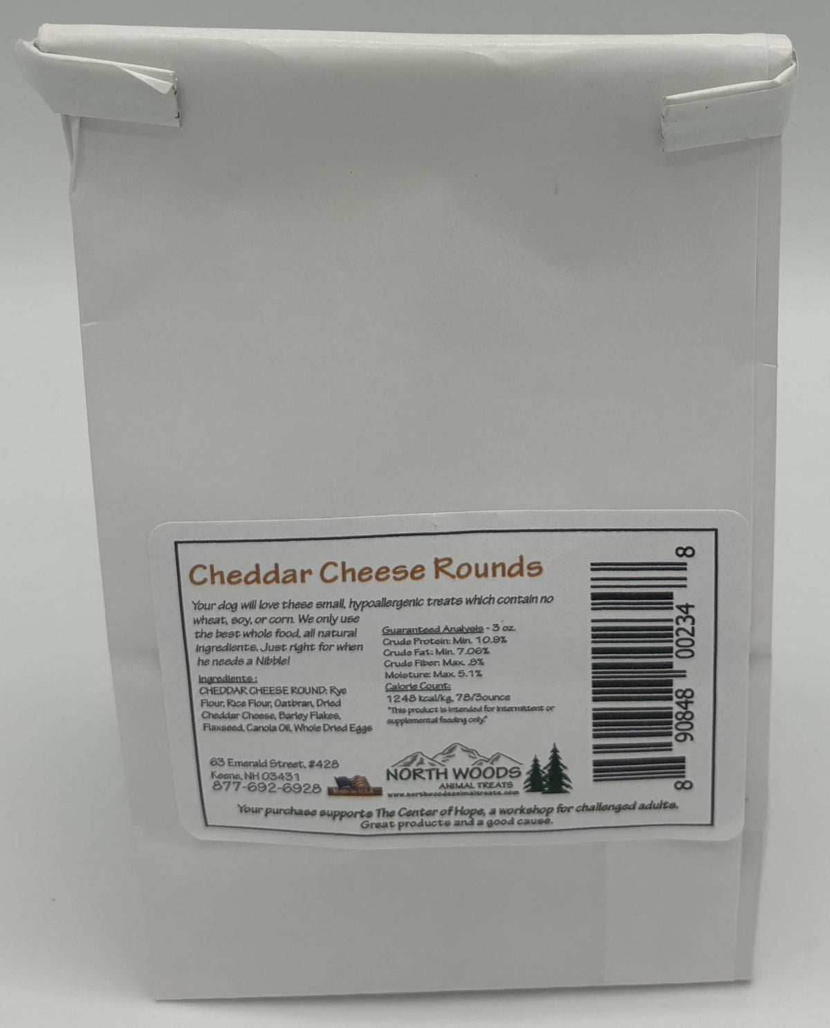 A white paper bag package of North Woods Cheese Rounds, showing a white label with product details, a barcode, and the North Woods logo.
