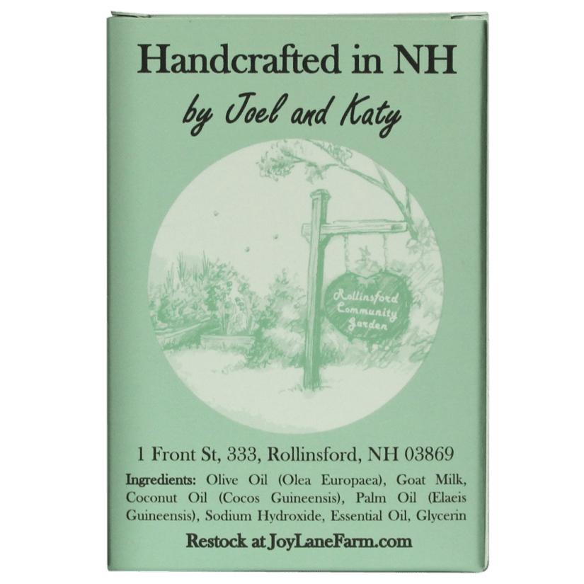 A rectangular mint-green product box with printed text reading 'Handcrafted in NH by Joel and Katy' and 'JoyLaneFarm.com' at the bottom, plus a circular illustration of a garden sign.