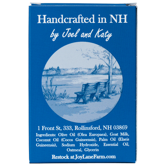 A blue rectangular box with white text reading 'Handcrafted in NH by Joel and Katy' and a circular blue-and-white illustration of a bench by a lake. The box also includes an address and Restock at JoyLaneFarm.