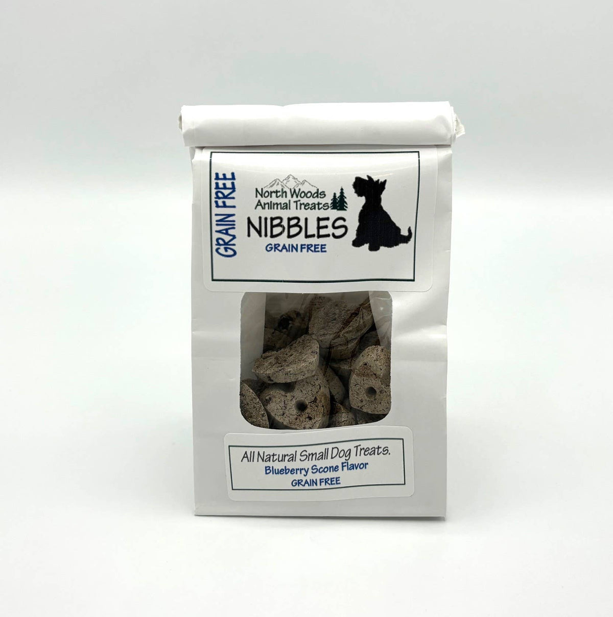 A white bag of North Woods Animal Treats Nibbles grain-free small dog treats with a clear window showing the treats inside, on a white background.