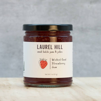 Jar of Laurel Hill Wicked Good Strawberry Jam on a wooden surface with a gray background