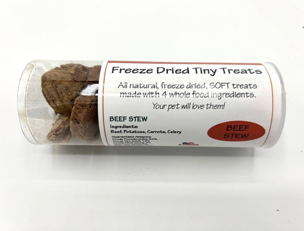A clear plastic tube containing freeze dried beef stew treats, with a white paper label that reads 'Freeze Dried Tiny Treats' and 'BEEF STEW'.
