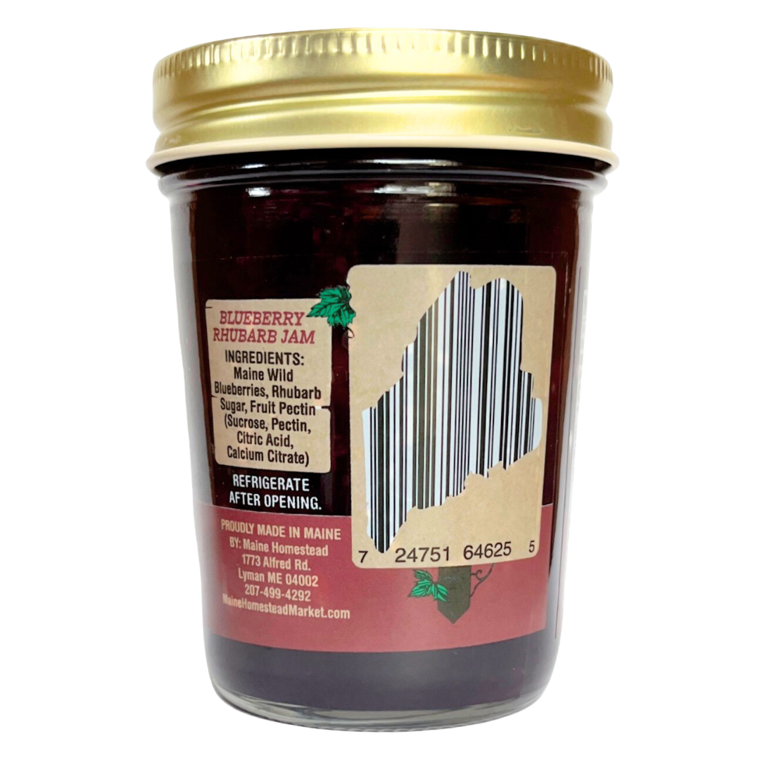 A glass jar of Blueberry Rhubarb Jam with a gold metal lid, showing the back label with a barcode and product details on a white background.