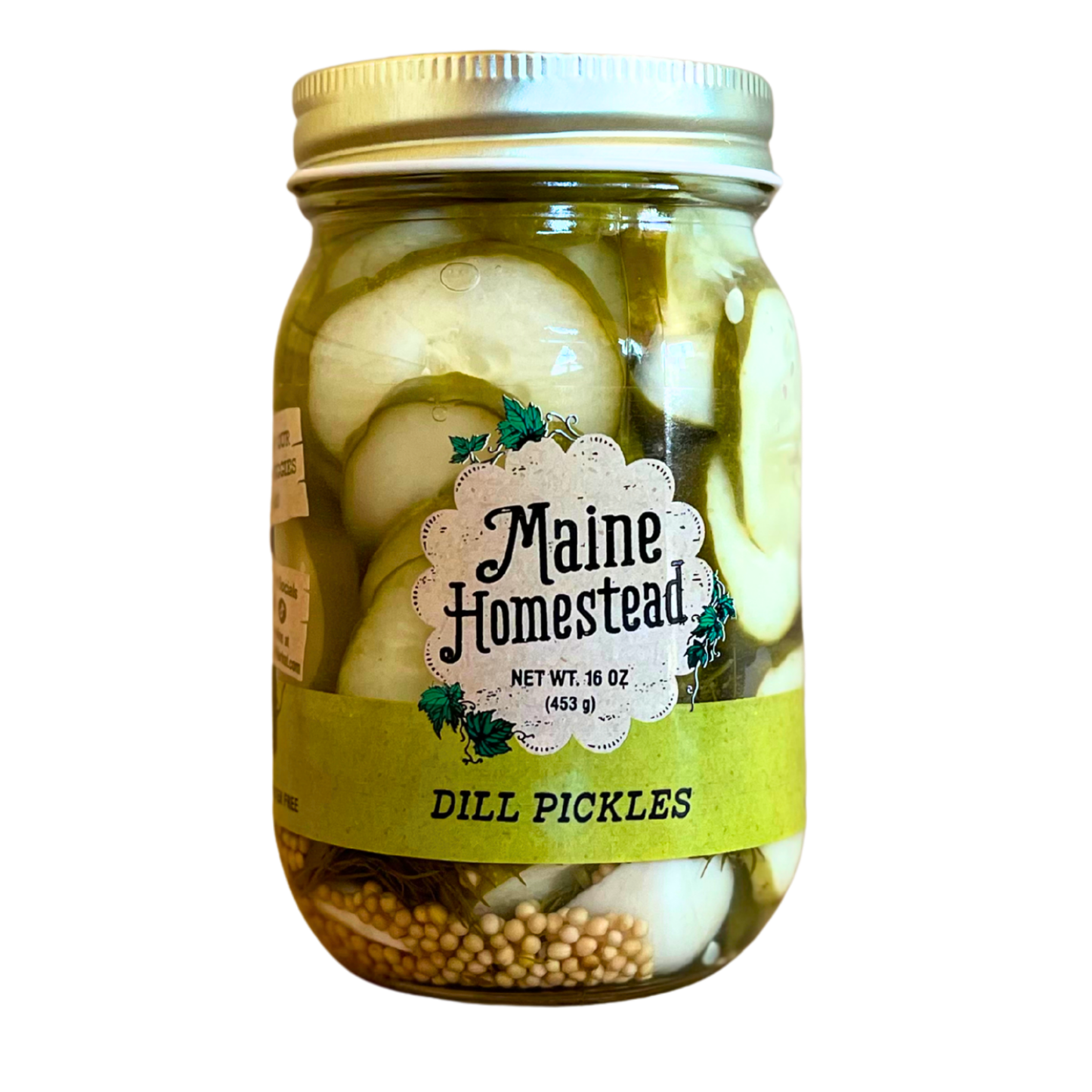 A glass jar of Maine Homestead Dill Pickles with a gold metal lid and a white and green label, containing sliced dill pickles and mustard seeds, isolated on a white background.