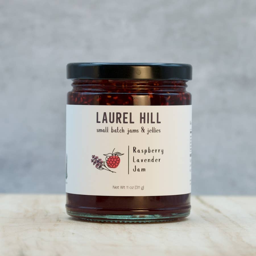 Jar of Laurel Hill Raspberry Lavender Jam on a wooden surface with a gray background
