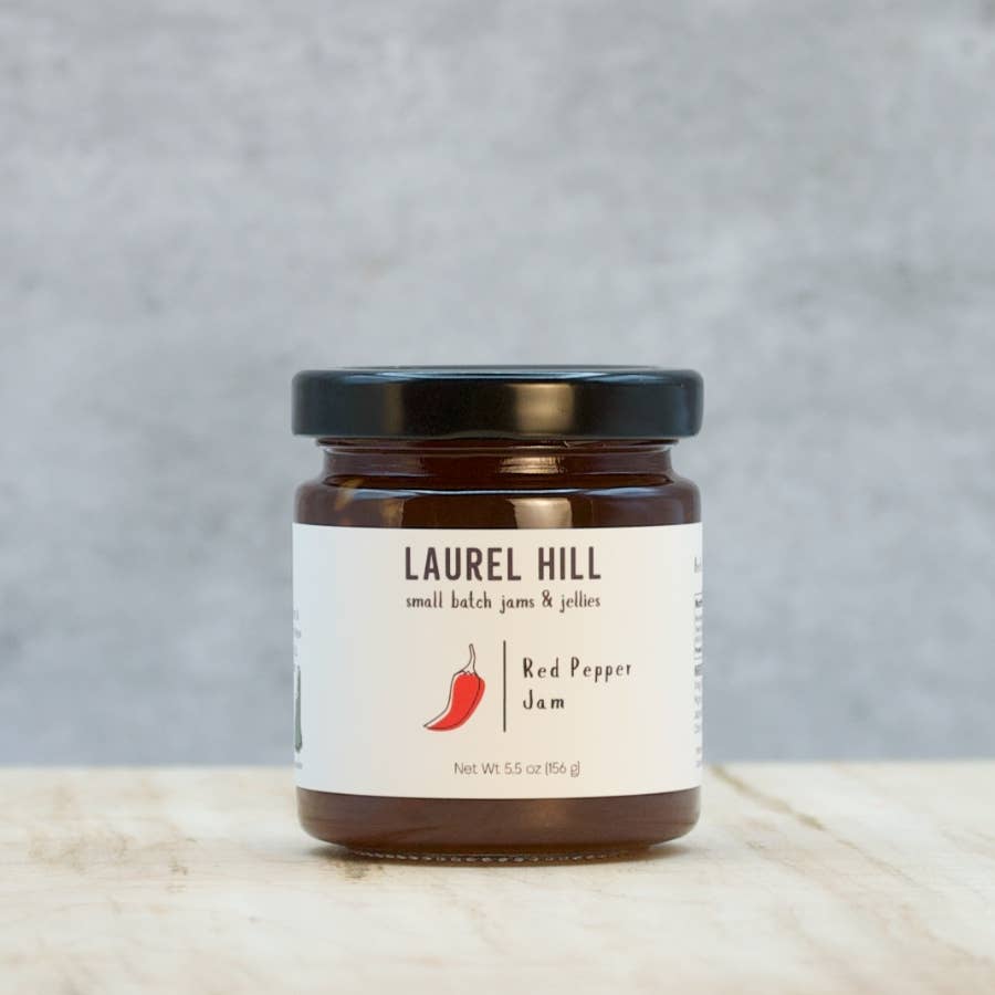 Jar of Laurel Hill Red Pepper Jam on a wooden surface with a gray background