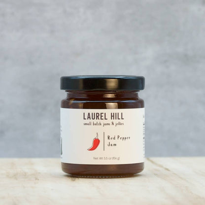 Jar of Laurel Hill Red Pepper Jam on a wooden surface with a gray background